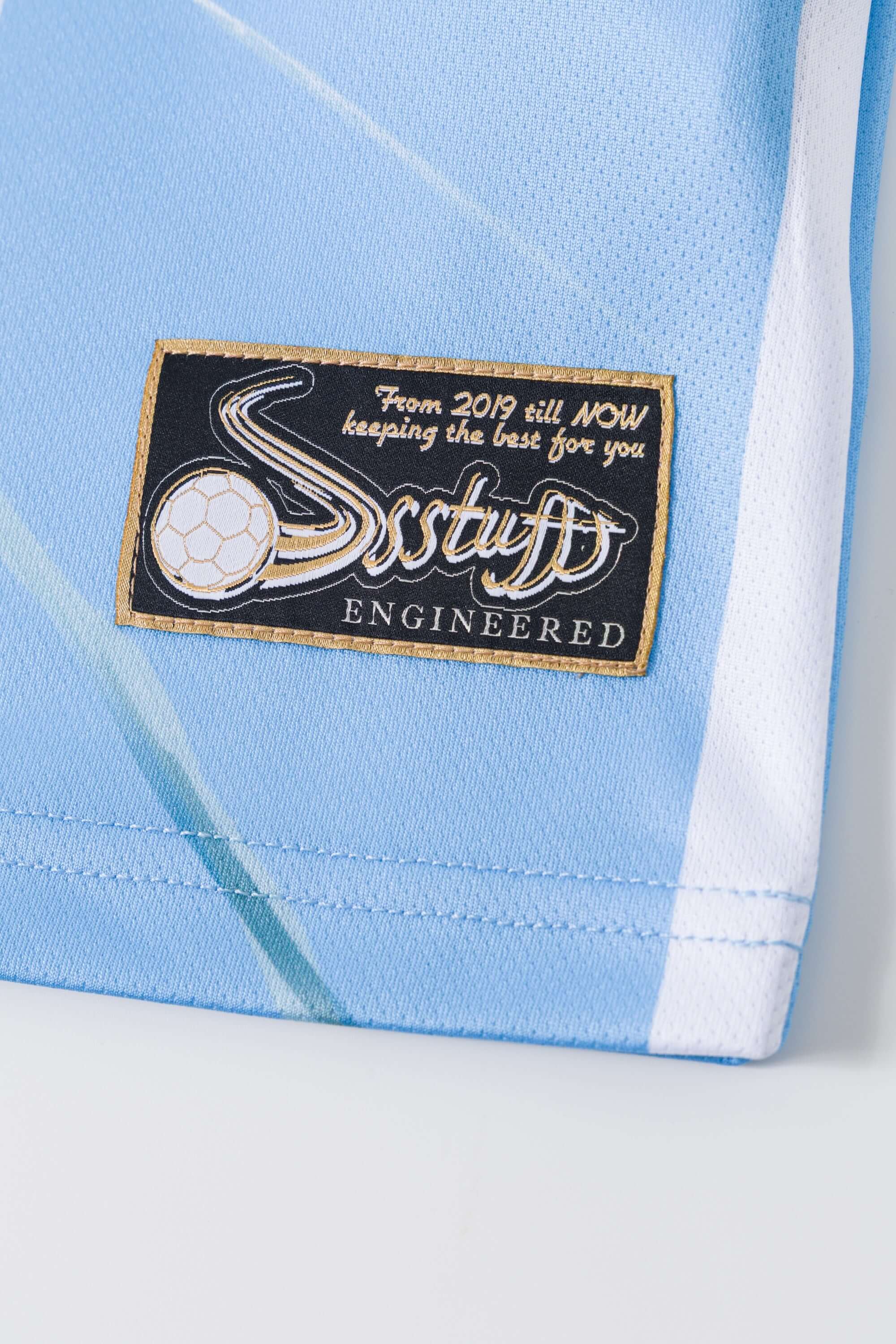 Close-up of a light blue and white sports jersey with a brand label on a white background
