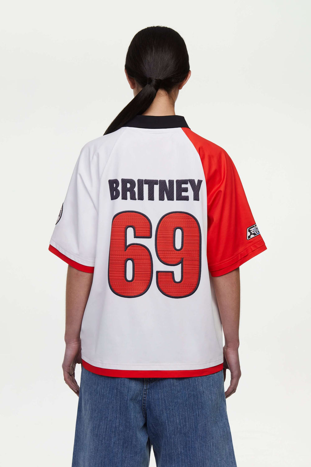 Person wearing white sports jersey with red and black accents, featuring the name 'Britney' and number '69' printed, mimicking embroidered in red and black