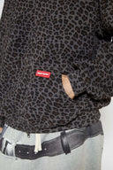 Leopard print zip up with a red label on a light gray background