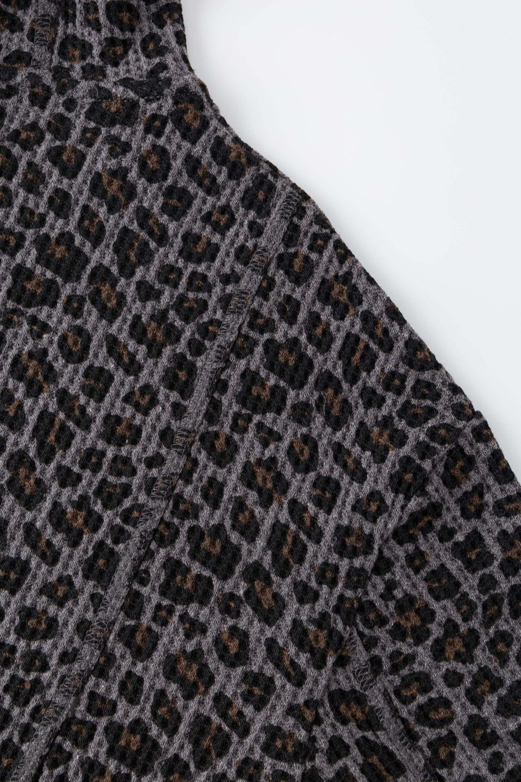 Leopard print zip up with a red label on a light gray background