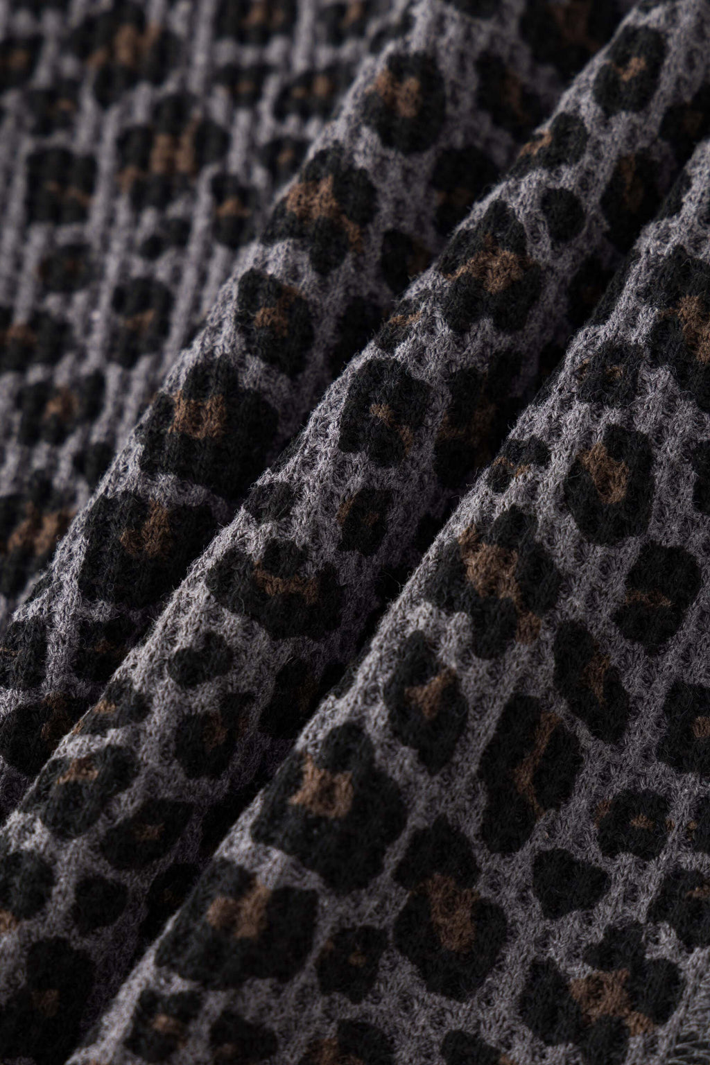 Leopard print zip up with a red label on a light gray background