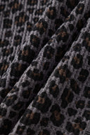 Leopard print zip up with a red label on a light gray background