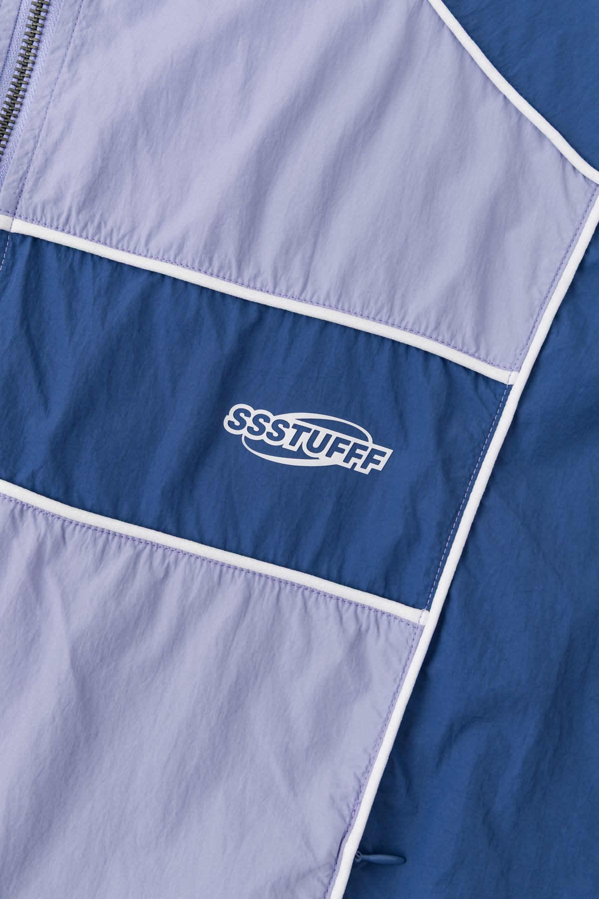 Detail of the SSSTUFFF chest logo on the blue panel.