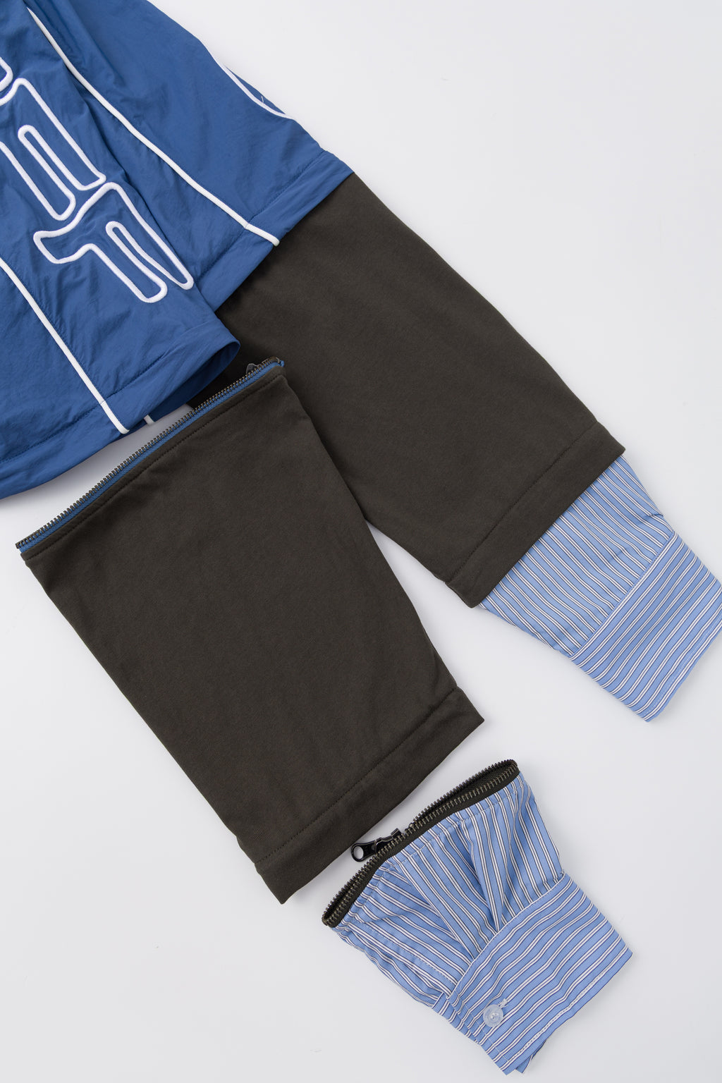 The three pieces separated and laid out: the track top, the dark sleeve layer and the striped shirt cuff.