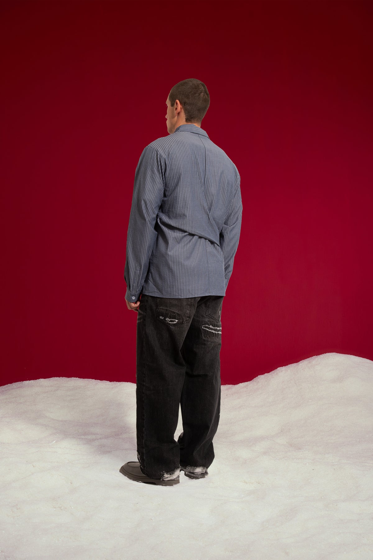 4 Sleeves Button Up Shirt in navy stripe, with two extra sleeves knotted at the waist. Worn on a model, full-length back view.