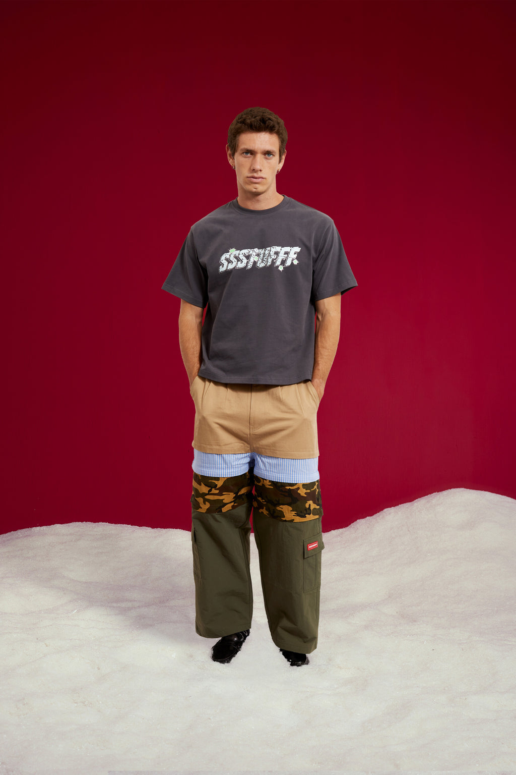 5 in 1 Layered Pants, five zip-together layers of khaki, stripe, camo and olive workwear. Worn on a model, full-length front view.