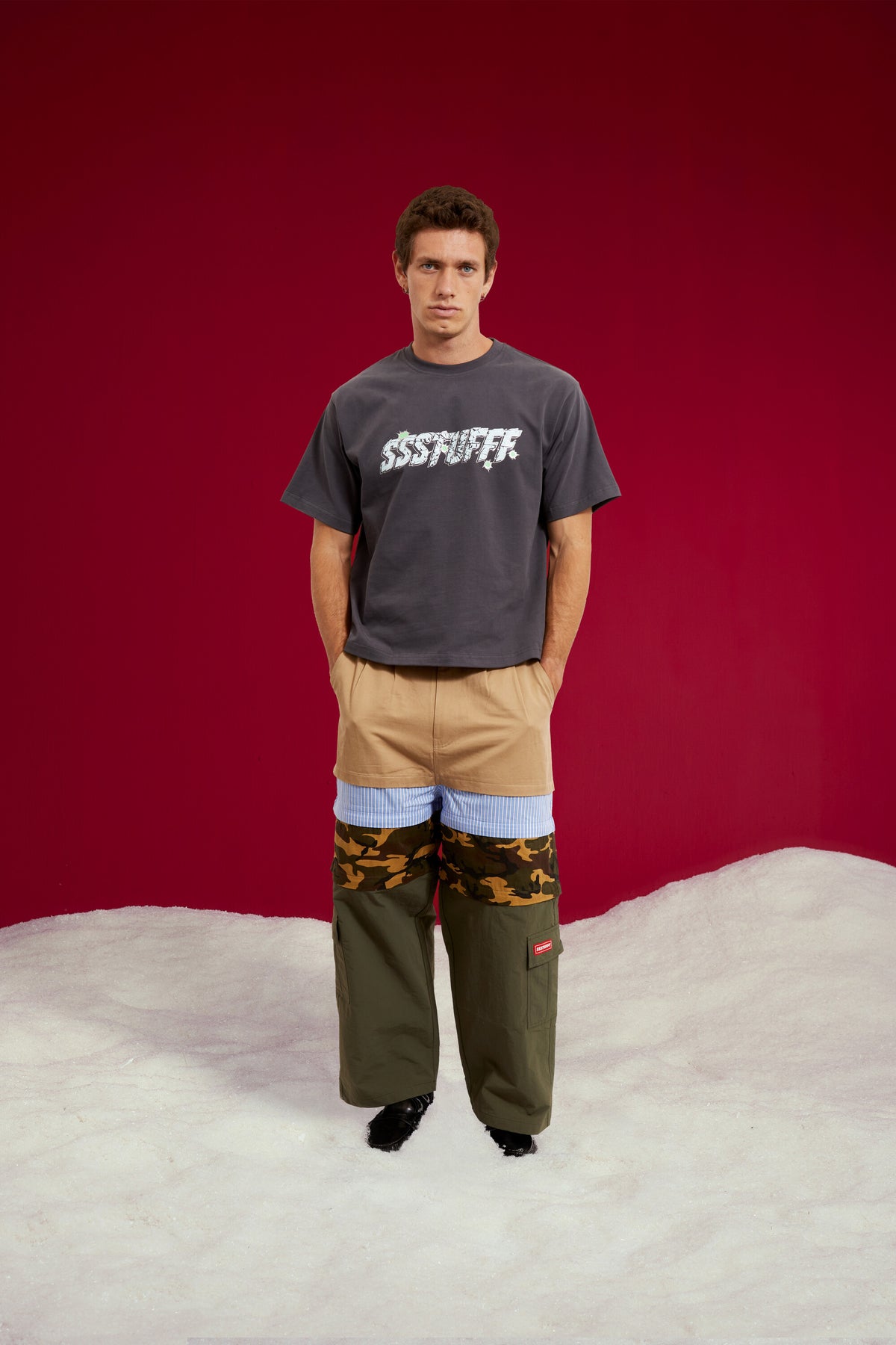 5 in 1 Layered Pants, five zip-together layers of khaki, stripe, camo and olive workwear. Worn on a model, full-length front view.