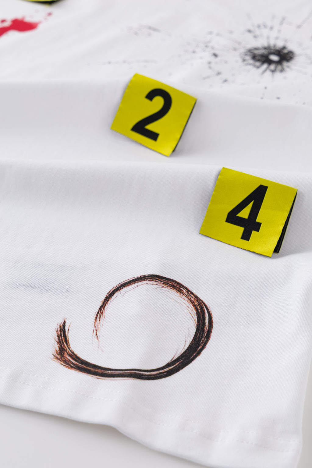 The tee laid flat, showing markers 2 and 4 standing up off the fabric beside the ring stain.