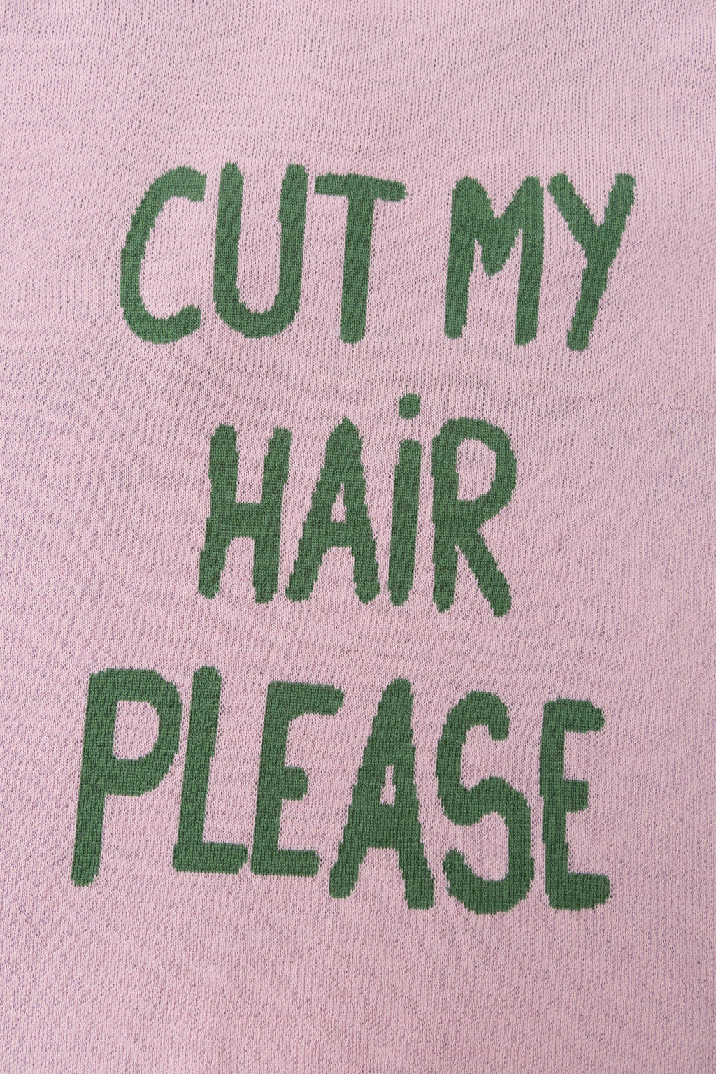 Detail of the CUT MY HAIR PLEASE lettering knitted into the back in green.