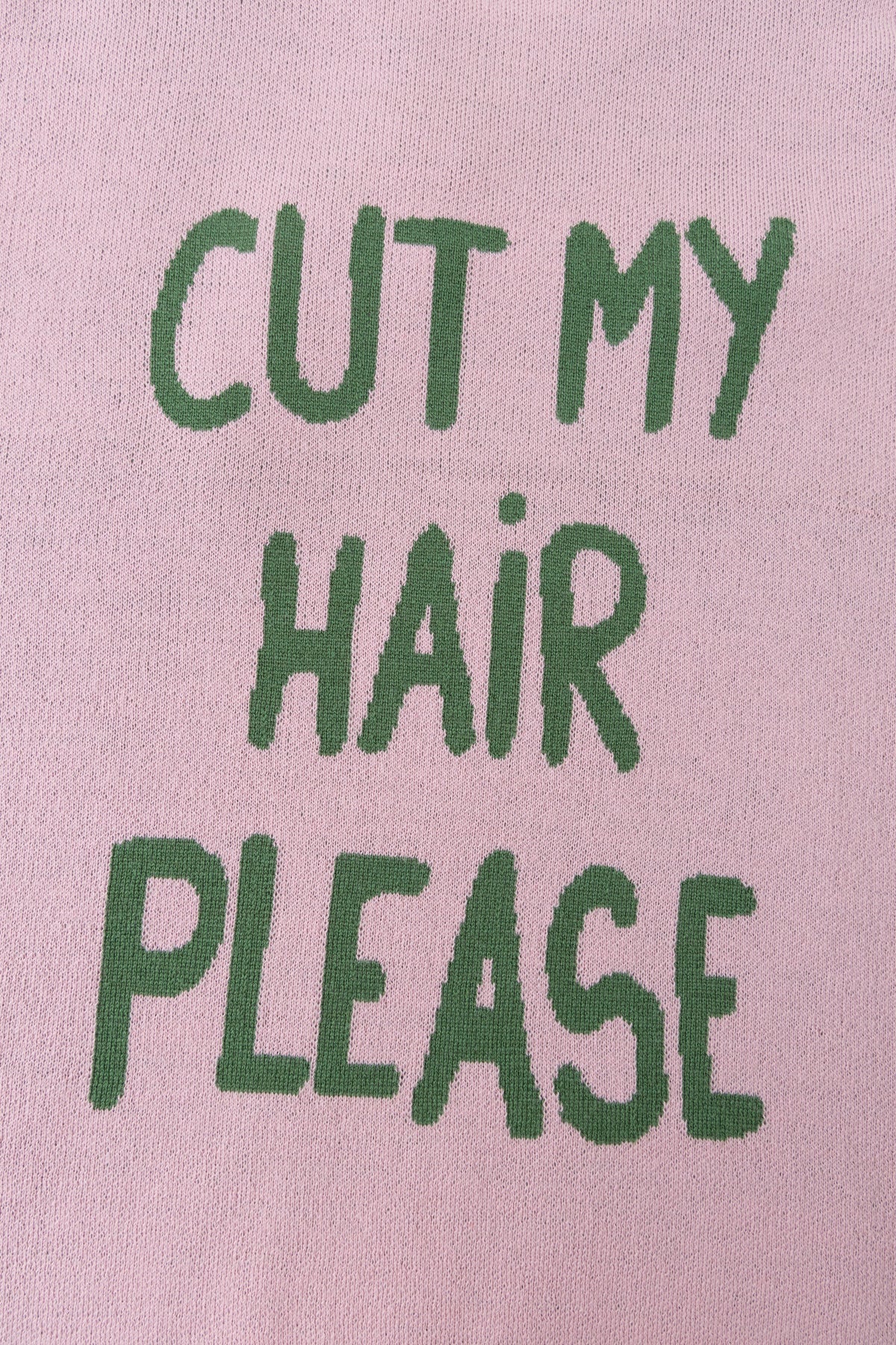 Detail of the CUT MY HAIR PLEASE lettering knitted into the back in green.