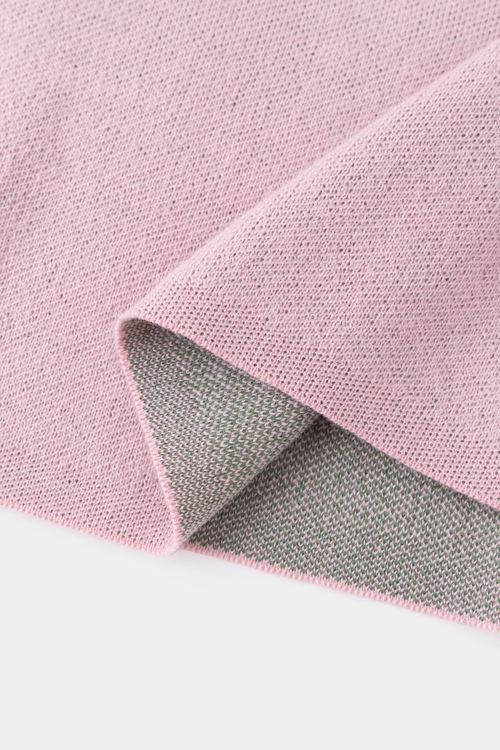 Close-up of the hem folded back, showing the grey reverse side of the pink knit.