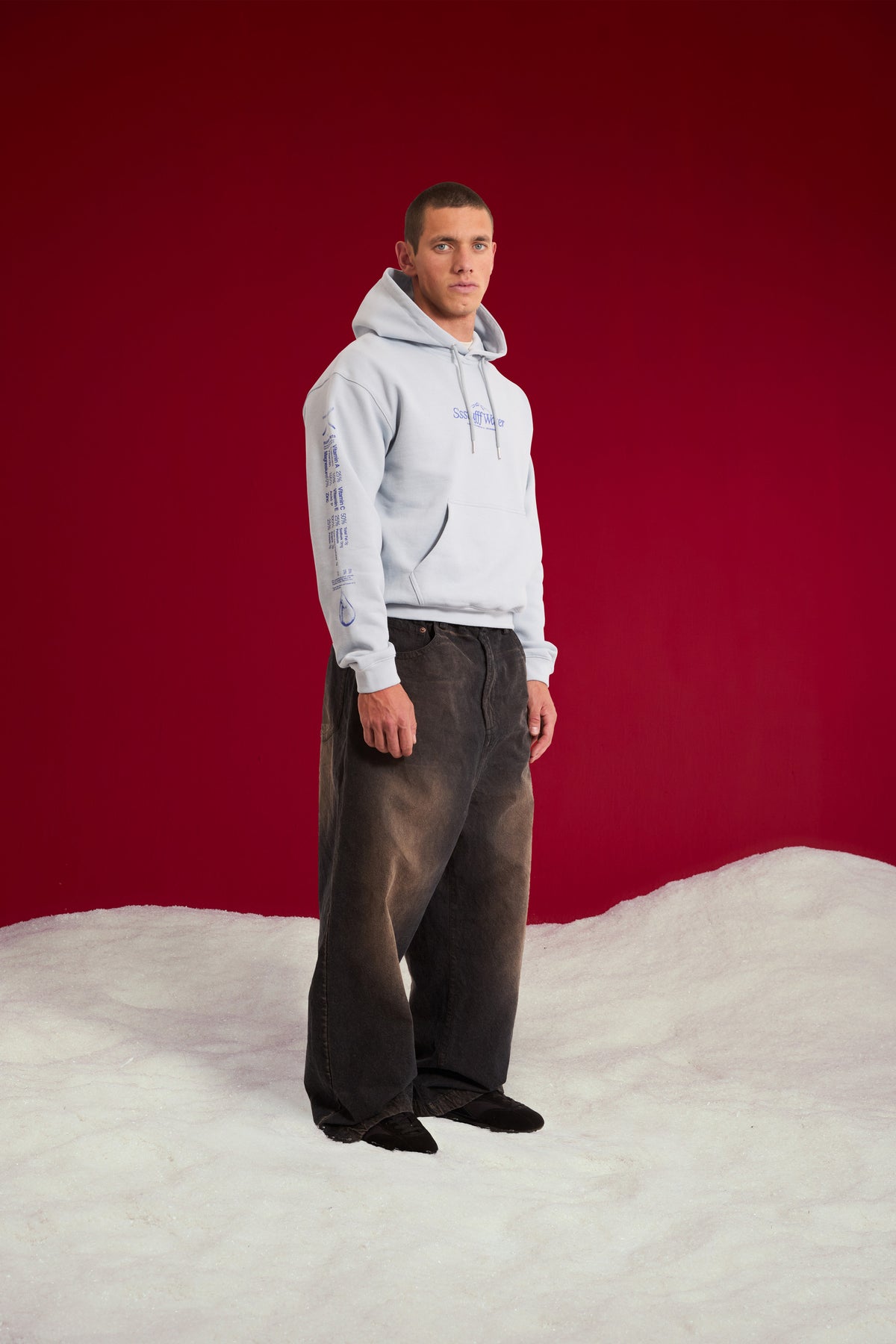 Cut & Reveal Water Hoodie in pale blue, printed with the Ssstufff Water logo at the chest. Worn on a model with the hood up, full-length front three-quarter view.