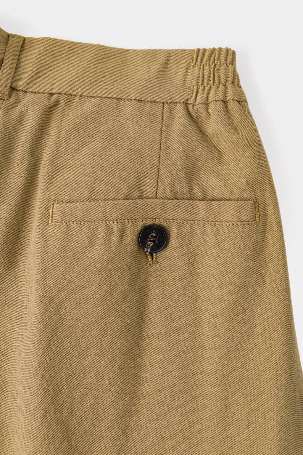 Close-up of the beige back welt pocket and its covered button.