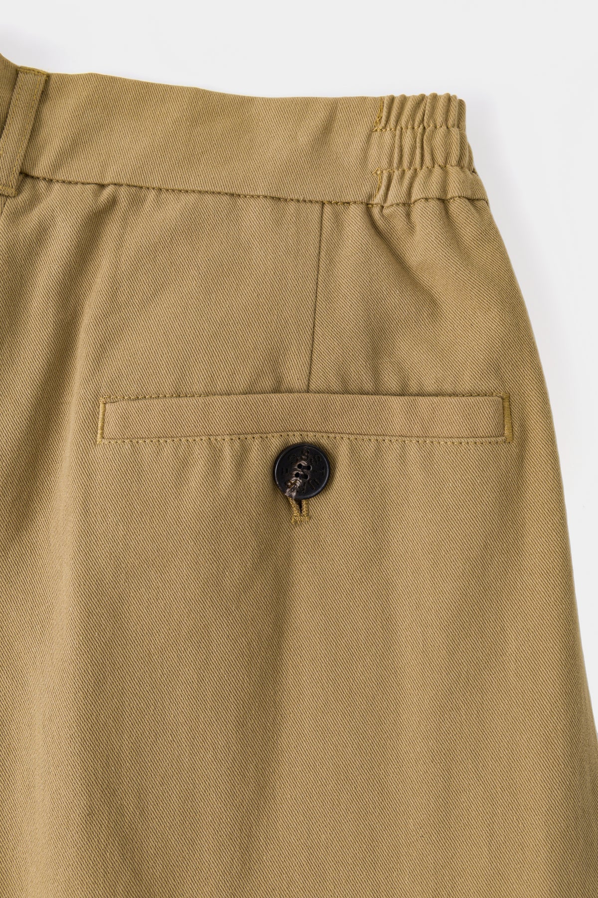 Close-up of the beige back welt pocket and its covered button.