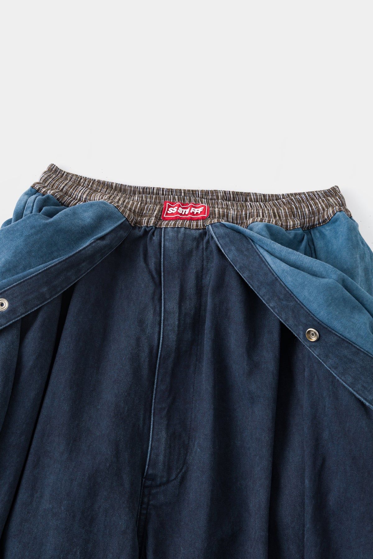 Close-up of the front waist: the striped elastic band, red Ssstufff label and the folded-down overall bib.