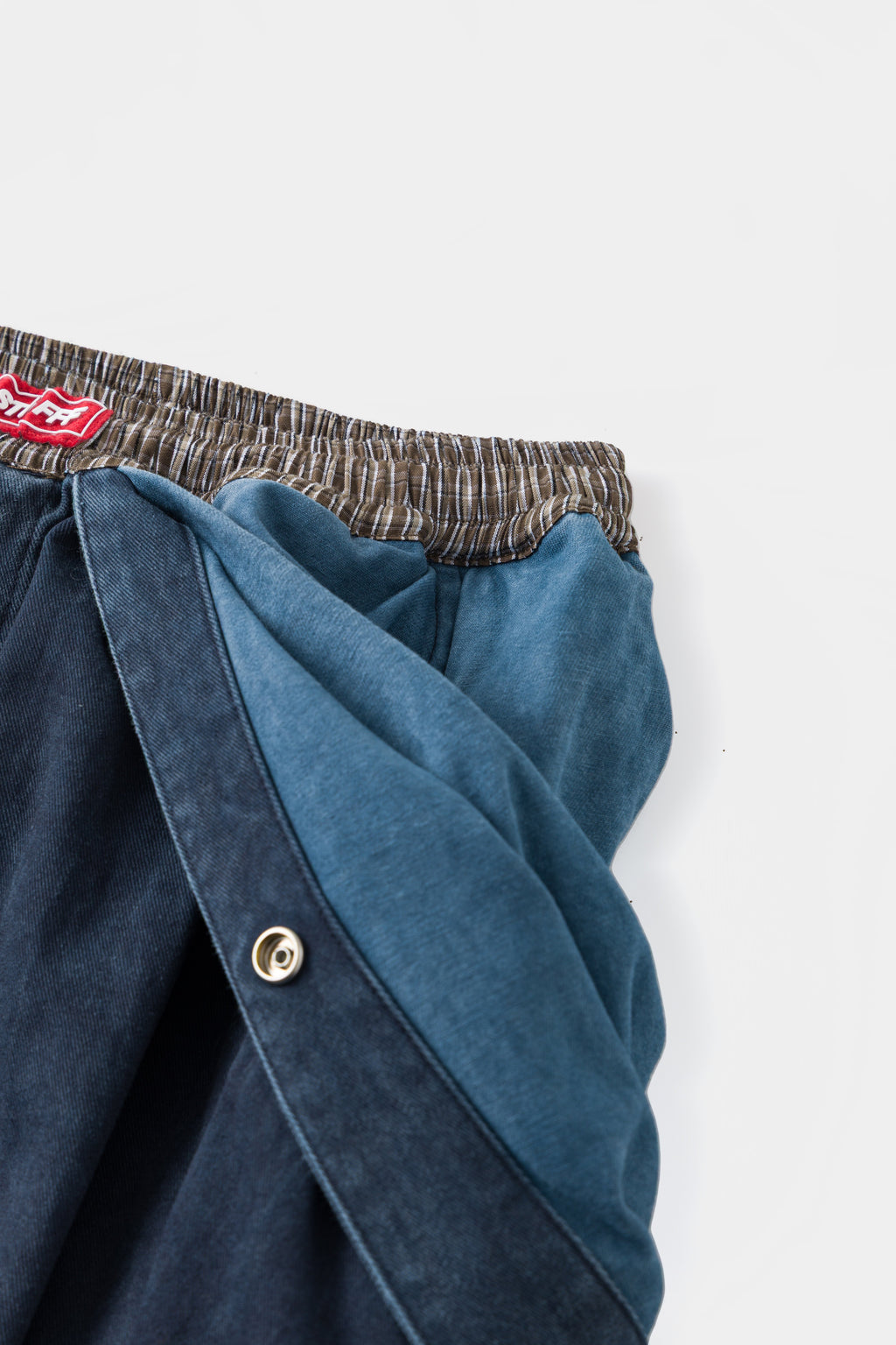 Detail of the snap fastener on the bib strap, with the lighter blue lining showing inside.