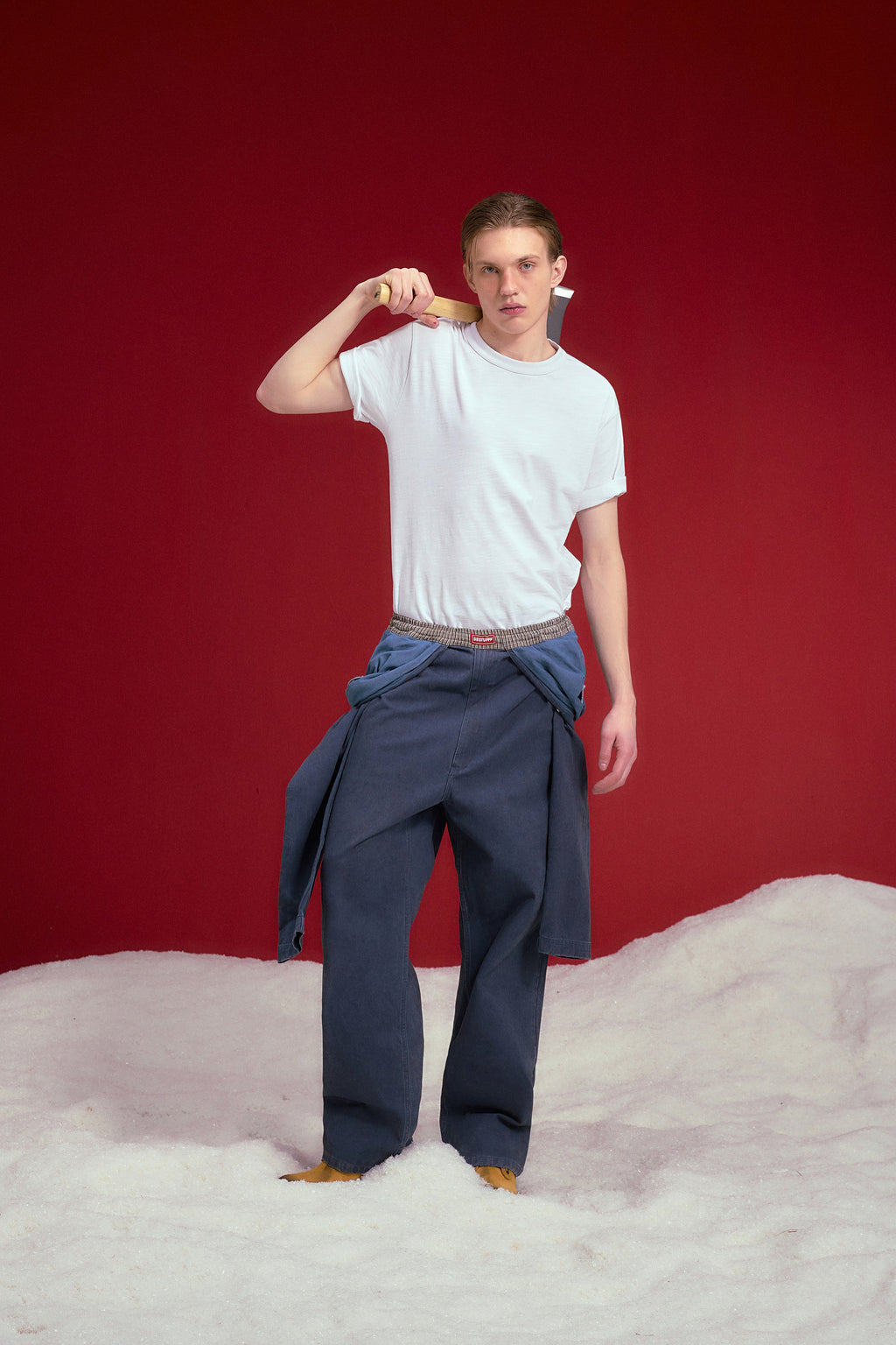 Fake Overall Pants in washed denim, with a fake overall bib and braces folded down at the waist. Worn on a model, full-length front view.