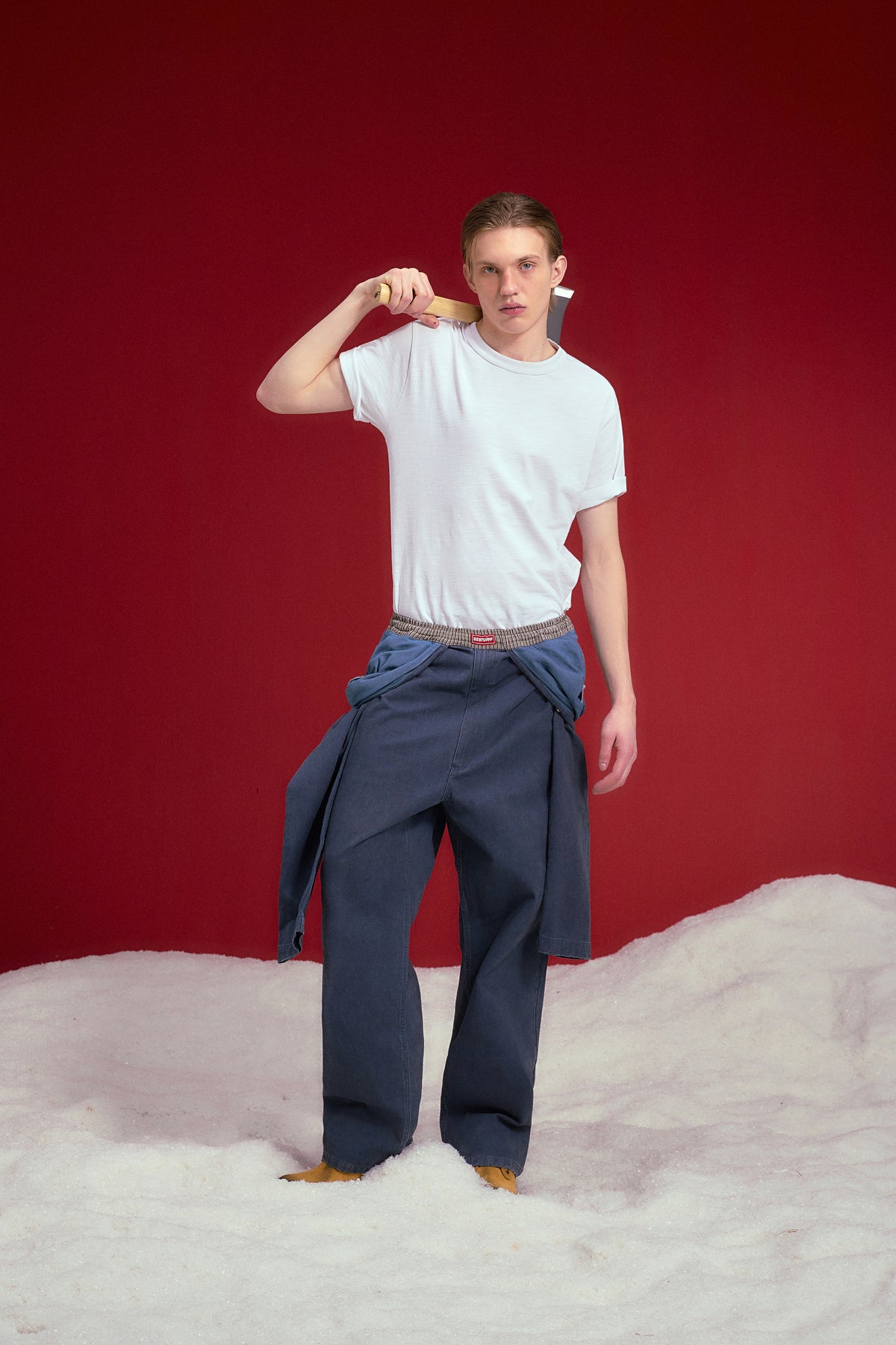 Fake Overall Pants in washed denim, with a fake overall bib and braces folded down at the waist. Worn on a model, full-length front view.