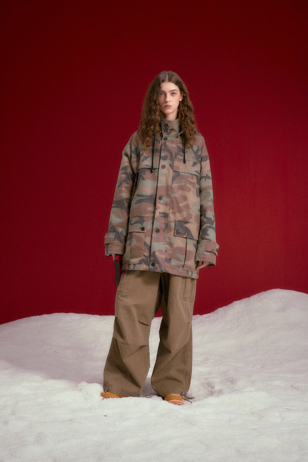 Faux Wax Camo Parka in woodland camo, with a detachable hood and multiple pockets. Worn on a model, full-length front view.