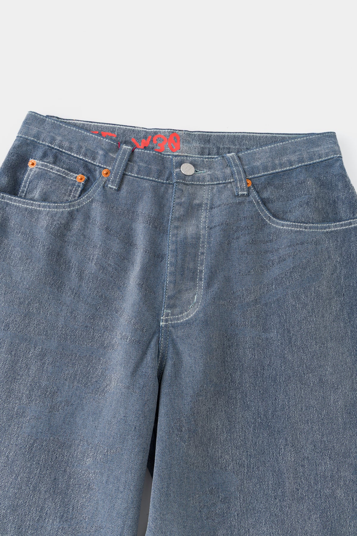 Close-up of the front waistband, button fly and coin pocket on the flocked denim.