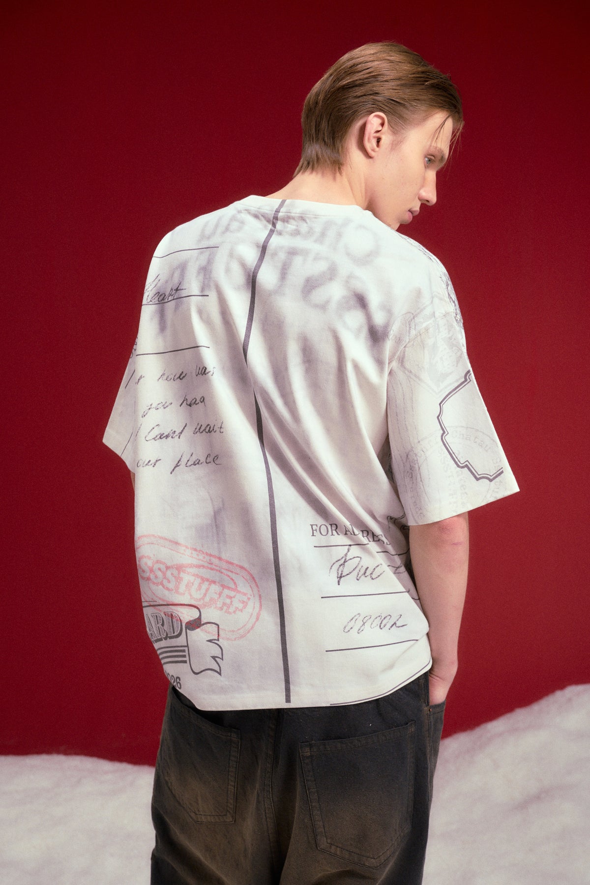 AOP Print Postcard Tee worn on a male model, waist-up back view.