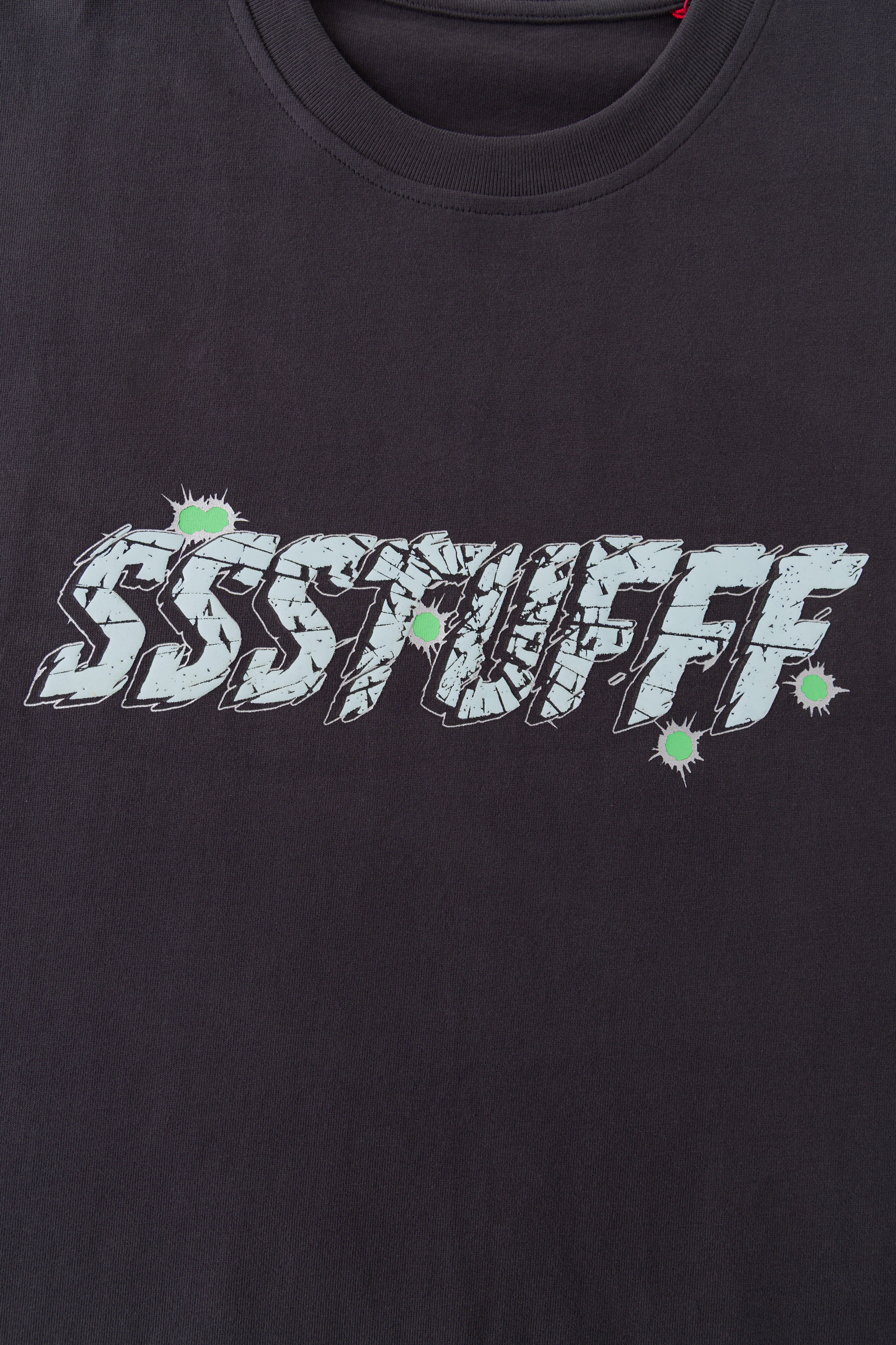 Close-up of the raised puff print SSSTUFFF shattered-glass graphic with green impact marks.