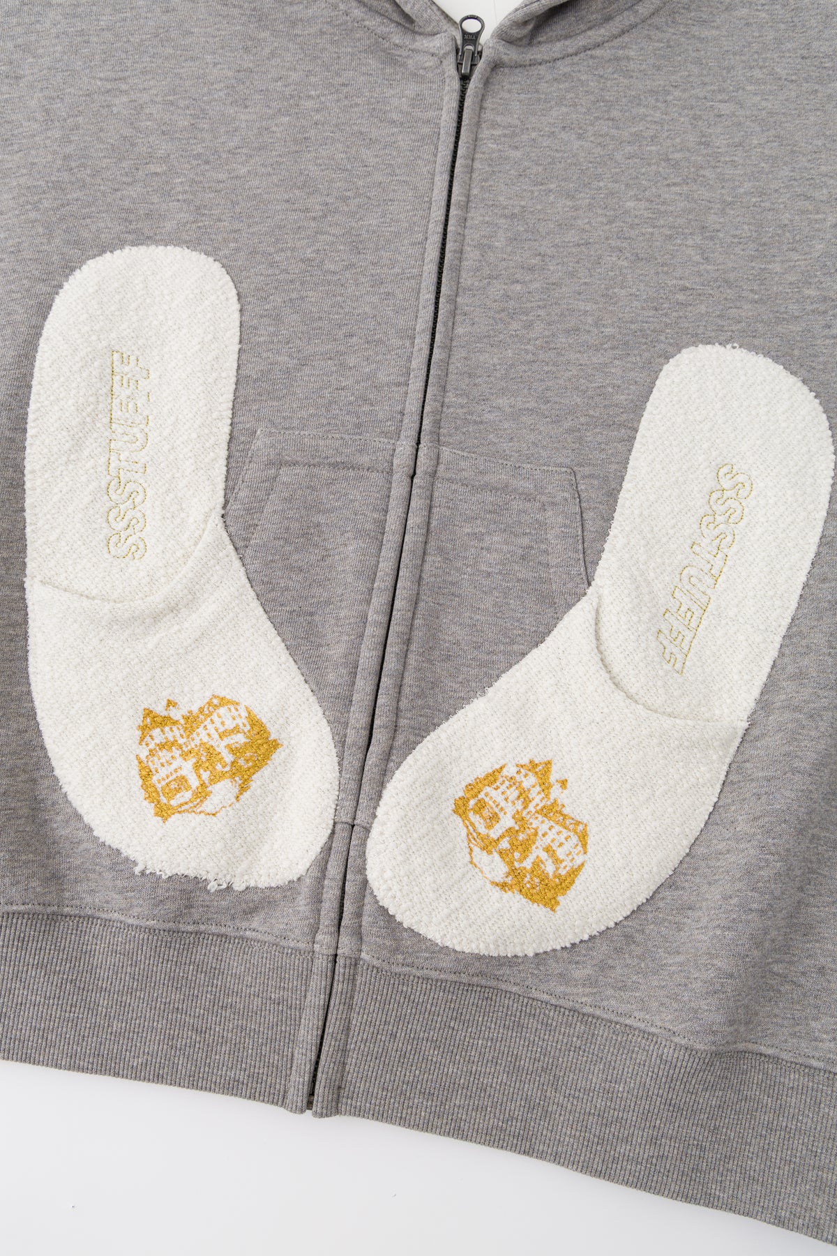 Close-up of the two towelling slipper patches with their gold embroidery.