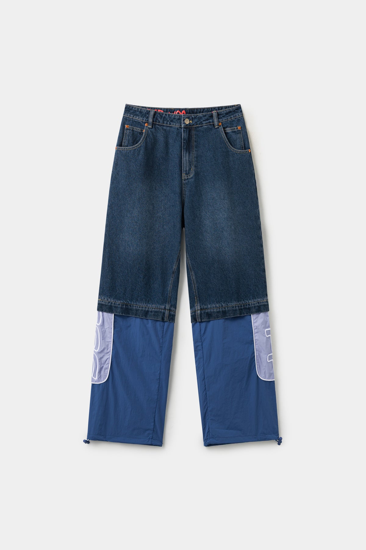 2 in 1 Hybrid Denim Trackpants in washed indigo, denim shorts zipped to blue nylon track legs with an oversized SSSTUFFF logo panel at the hem.