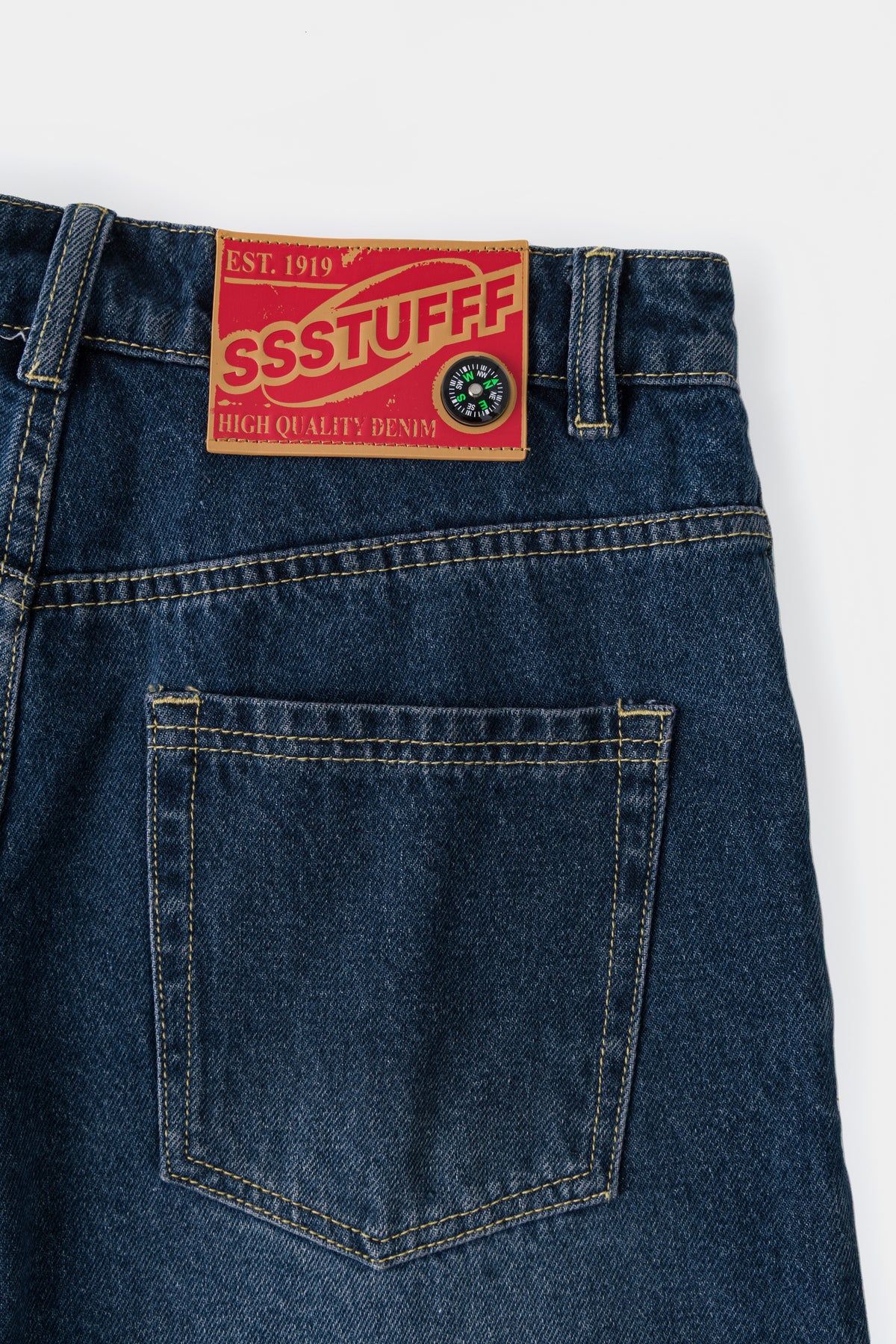 Detail of the back pocket and the red SSSTUFFF Est. 1919 denim label at the waistband.