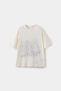 Inside Out Plumber Tee in cream, worn inside out so the plumber graphic shows faintly through the fabric.