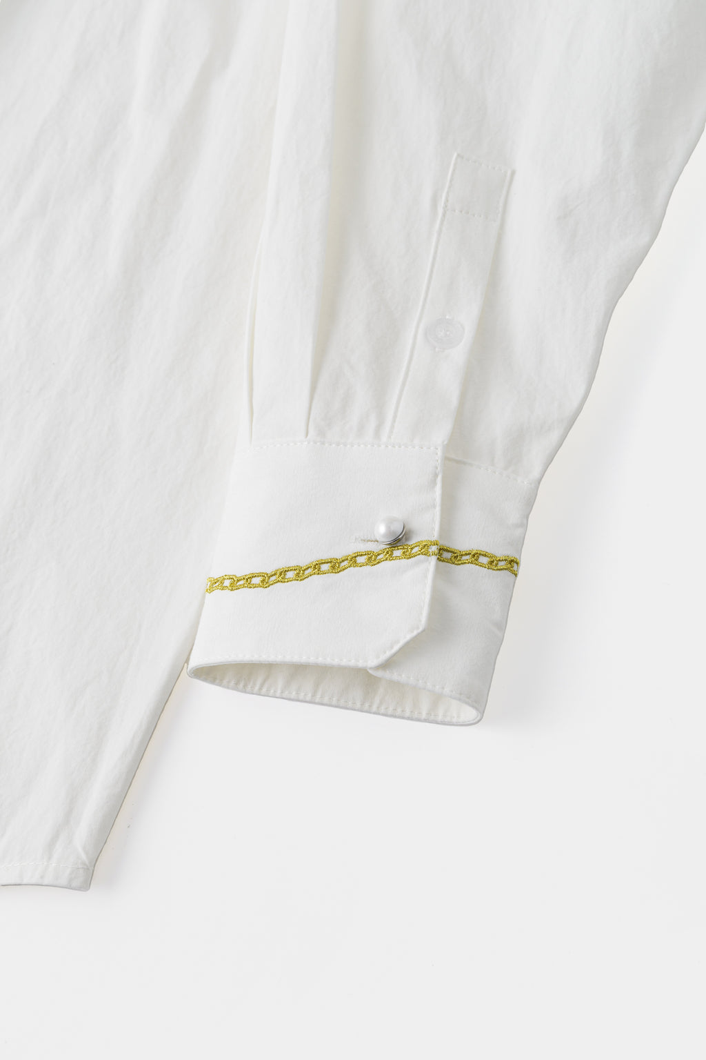 Close-up of the cuff, with an embroidered gold bracelet and a crystal button.