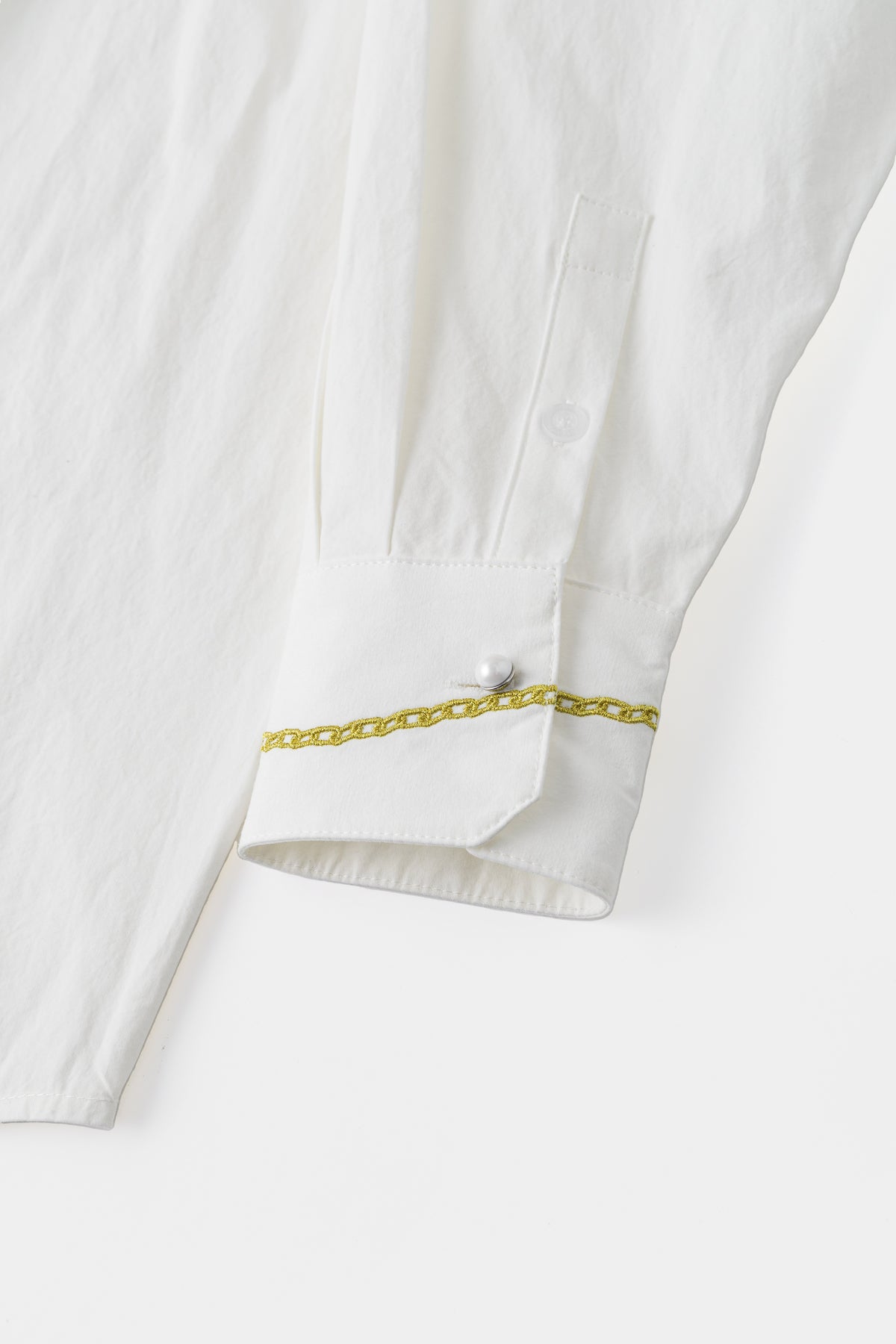 Close-up of the cuff, with an embroidered gold bracelet and a crystal button.