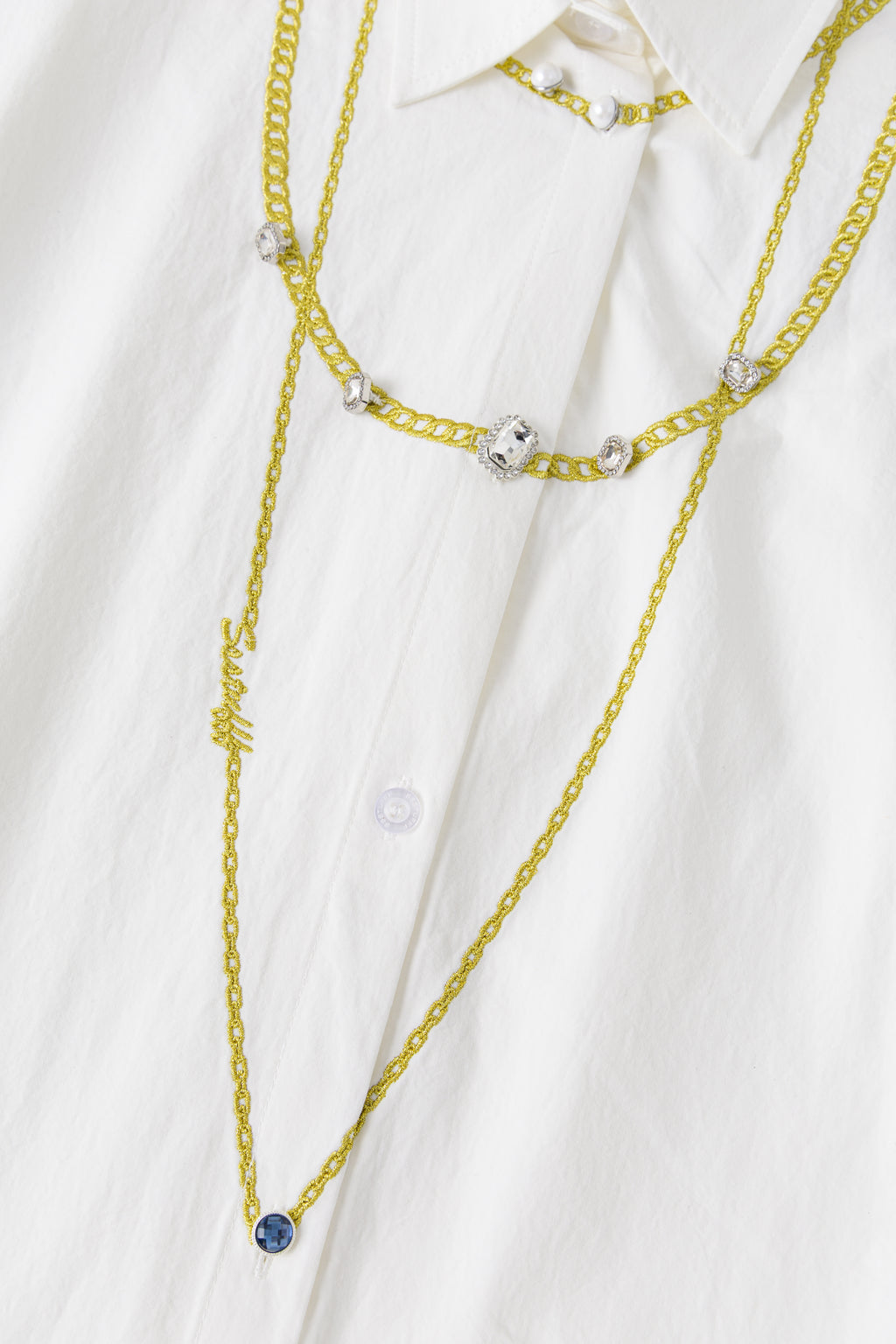 Detail of the embroidered chains down the chest, crystal buttons and the blue stone pendant at the end.