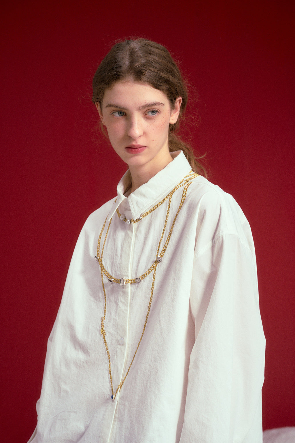 Fancy Embroidery Jewelry Shirt in off-white, embroidered with jewellery chains at the neckline. Worn on a model, waist-up view, close-up of the embroidered chain.