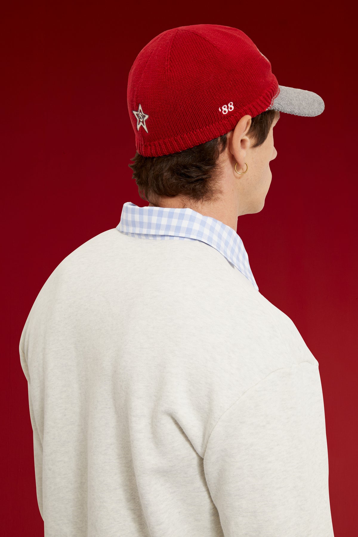 Red Knitted Cap with a contrast grey knitted brim and gothic ssstufff embroidery at the front. Worn on a model, close-up detail, back of the cap.