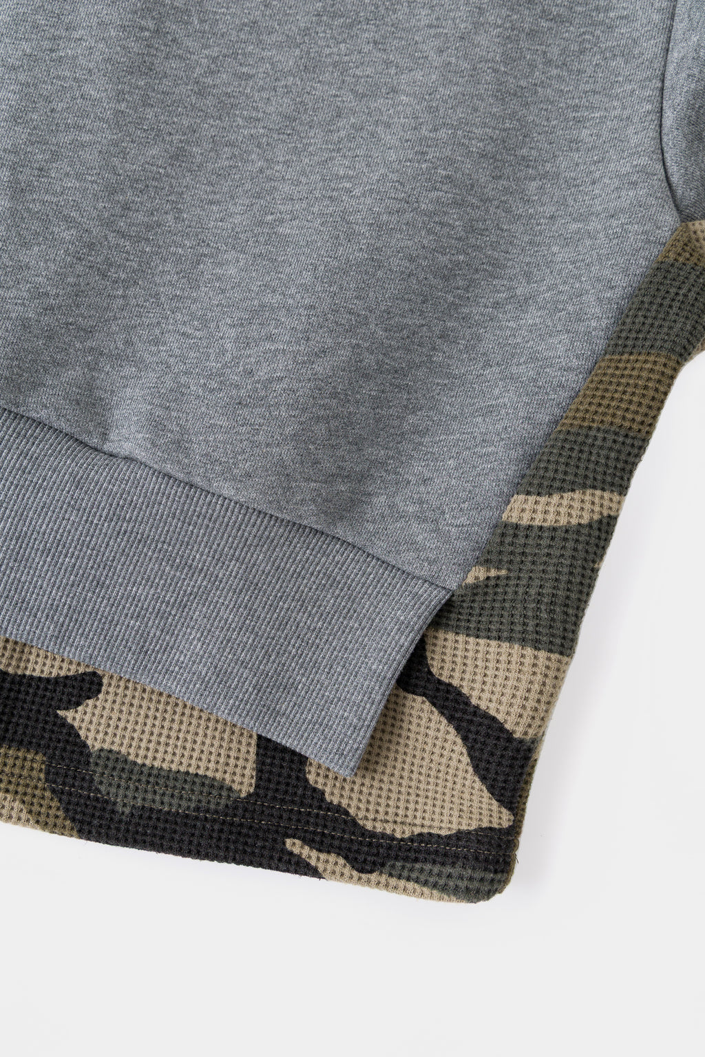 Detail of the waffle camo layer emerging under the ribbed hem.