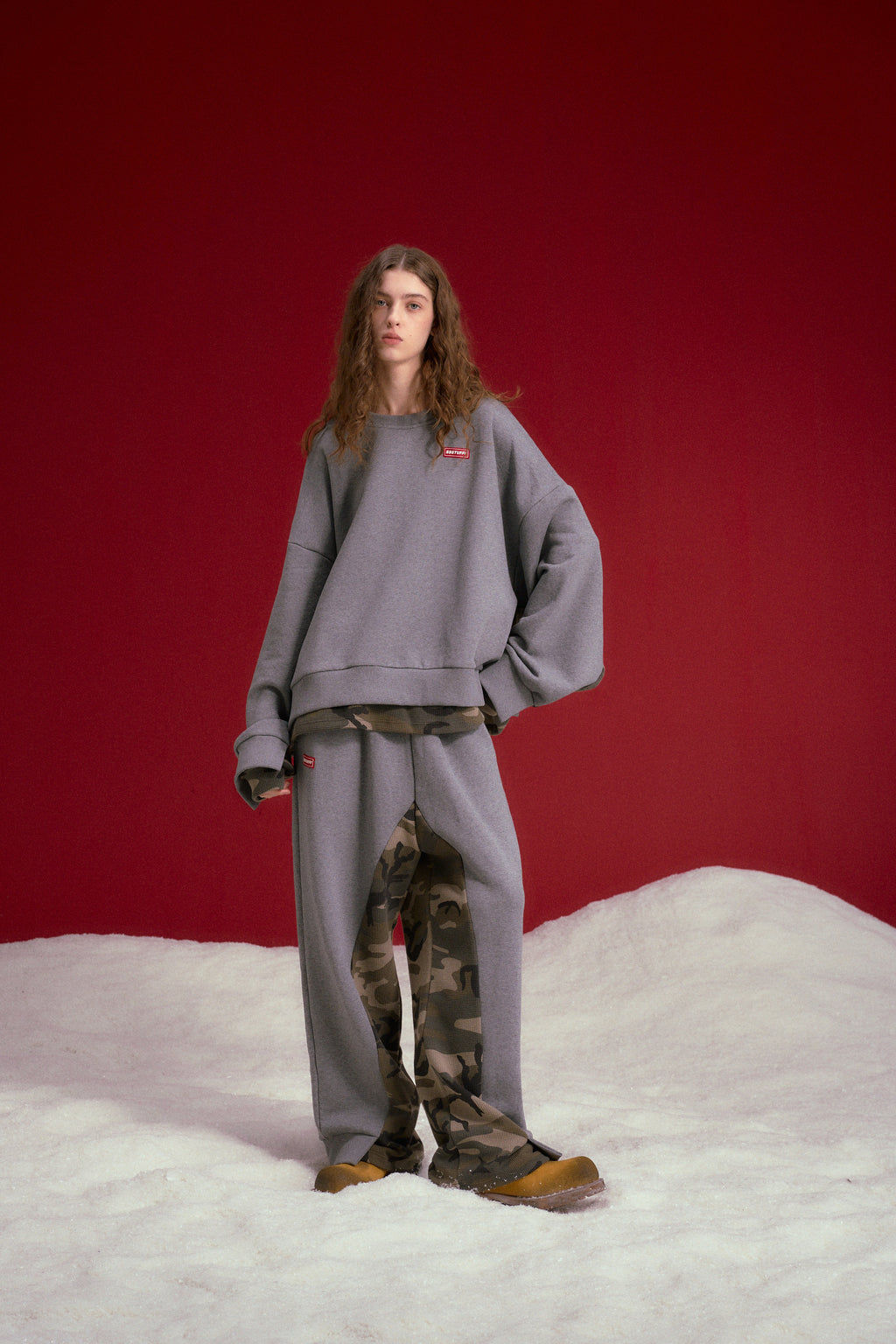 Layered Waffle Camo Crewneck in grey marl, with a waffle camo layer showing at cuffs and hem. Worn on a model, full-length front view.