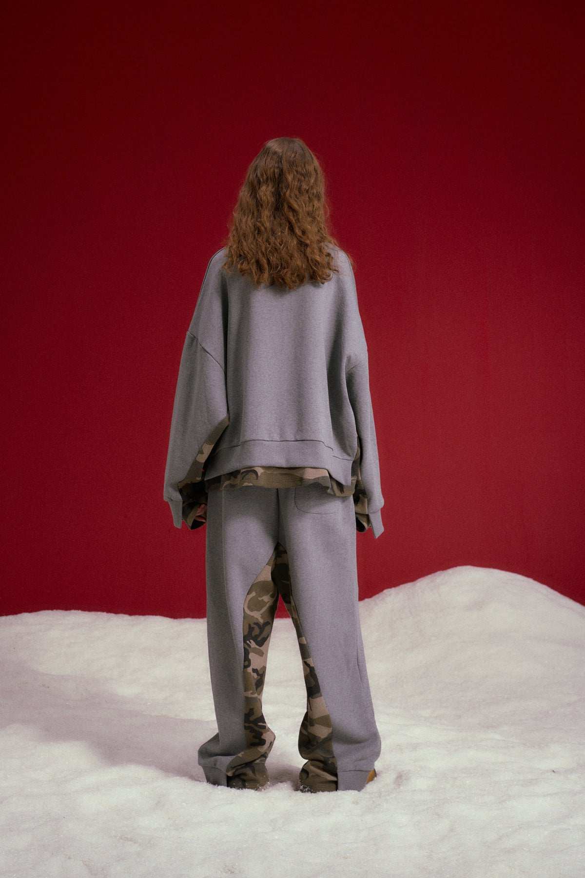 Layered Waffle Camo Crewneck in grey marl, with a waffle camo layer showing at cuffs and hem. Worn on a model, full-length back view.