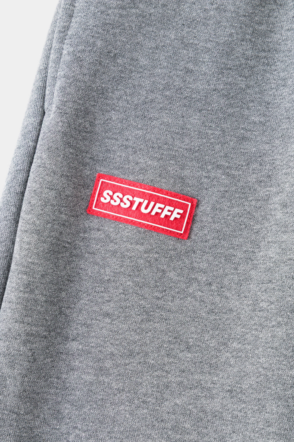 Detail of the red rubberised SSSTUFFF patch on grey loopback.