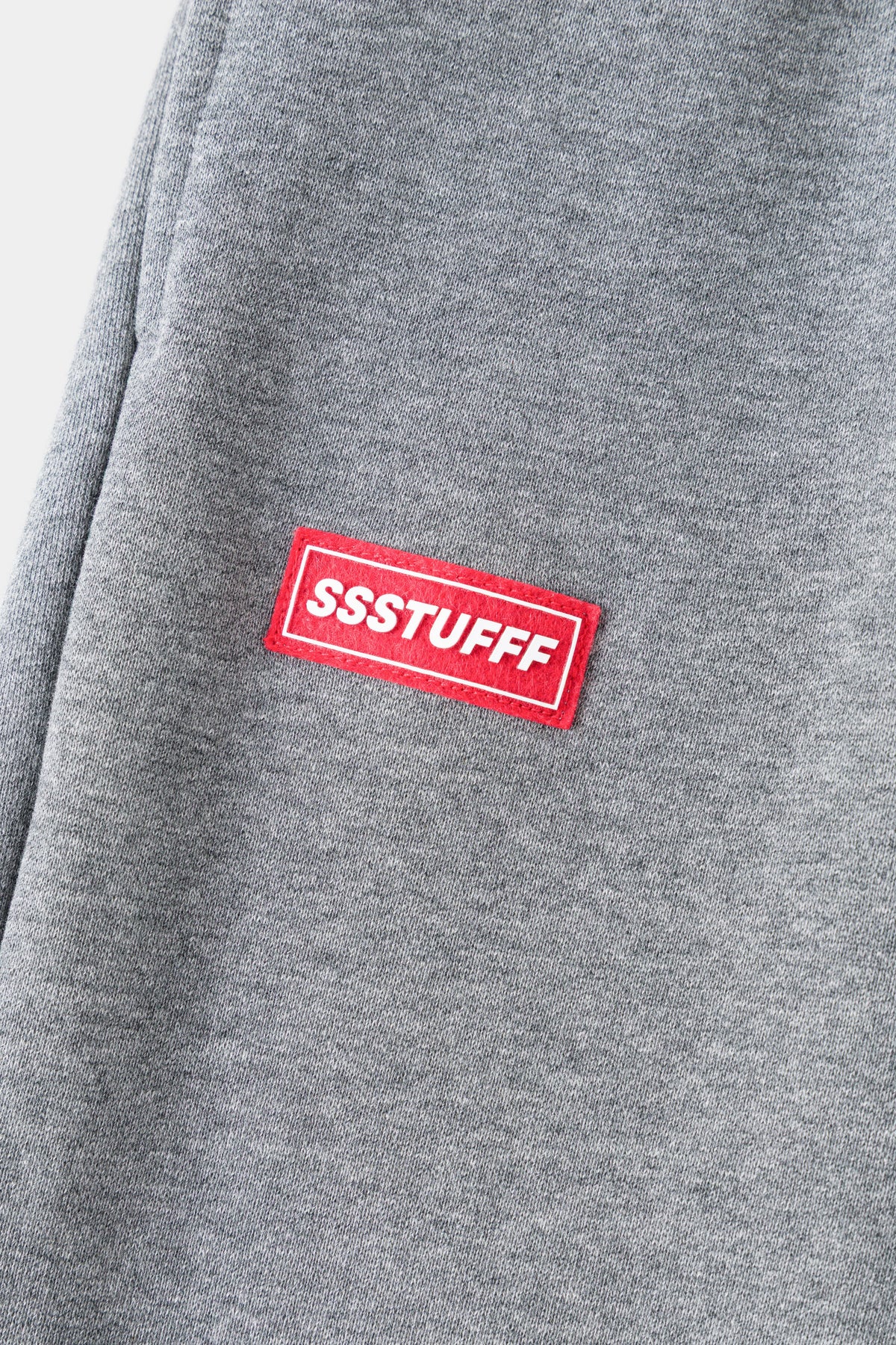 Detail of the red rubberised SSSTUFFF patch on grey loopback.