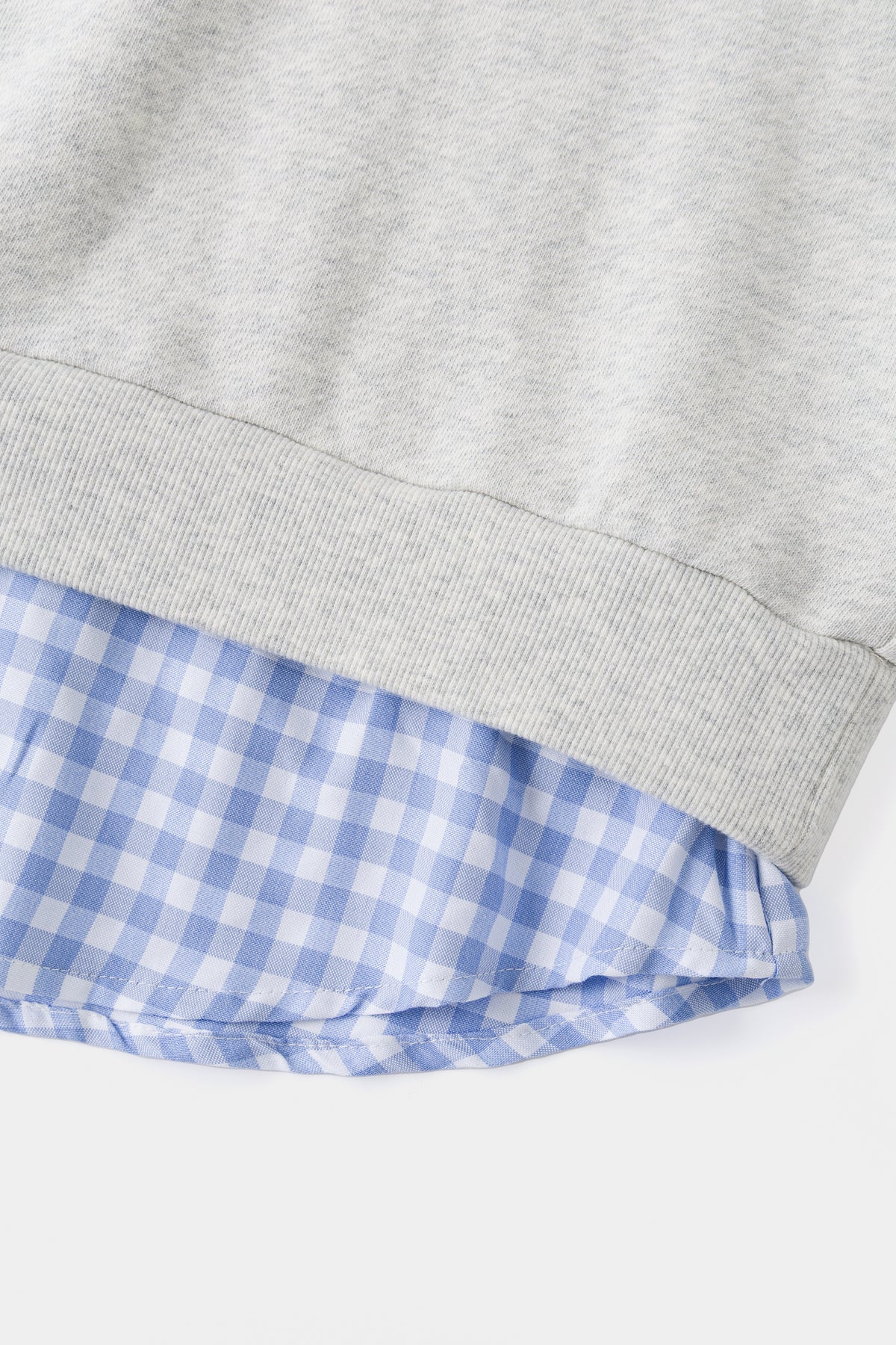 Close-up of the ribbed hem over the blue gingham shirt tail.