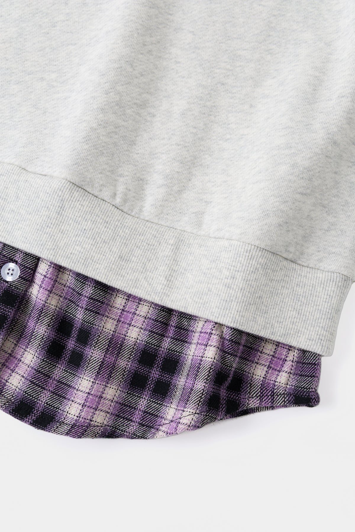 Close-up of the ribbed hem over the purple checked shirt tail.