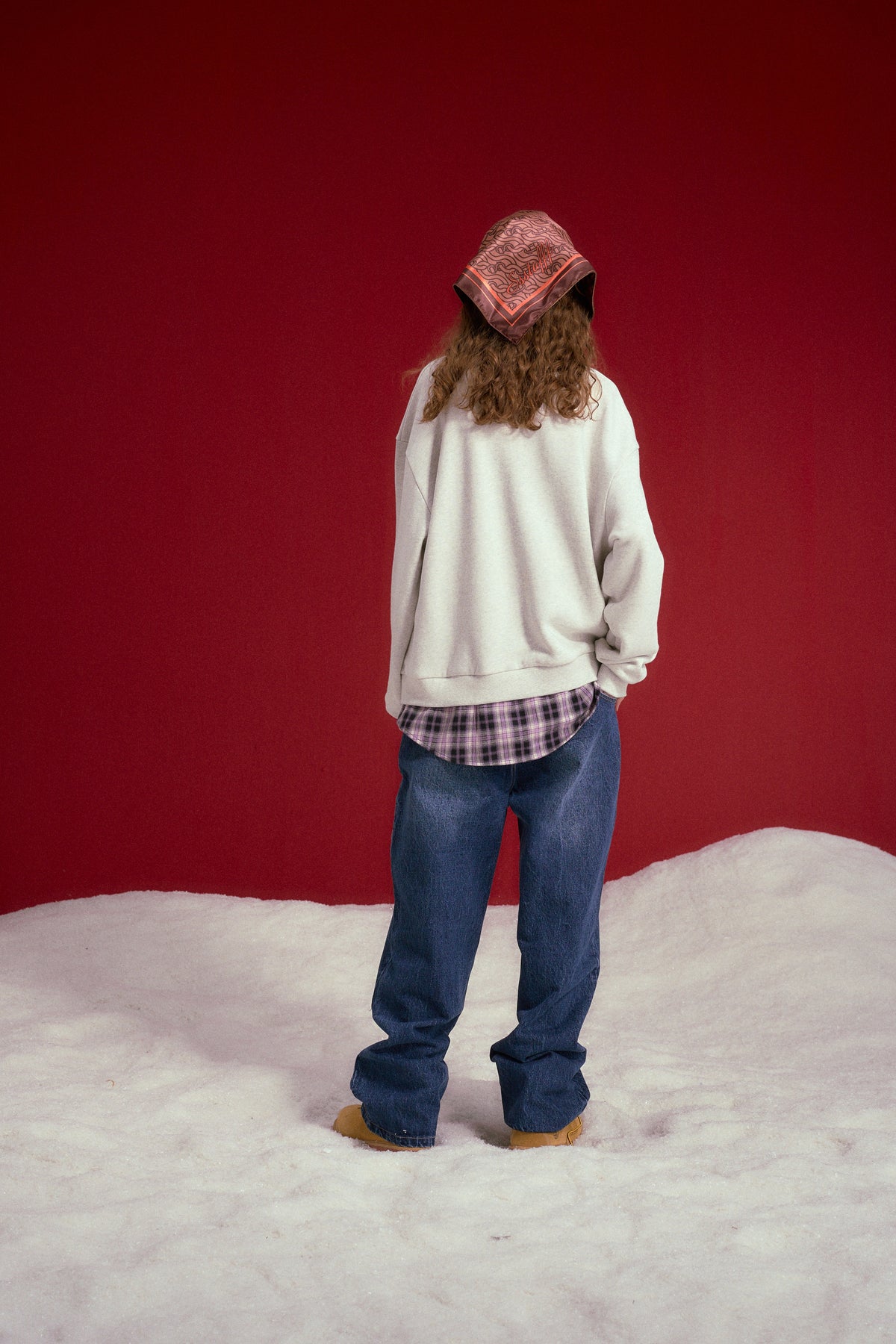 Layered Shirt Crewneck in oatmeal marl, spliced with a checked shirt collar and hem. Worn on a model, full-length back view.