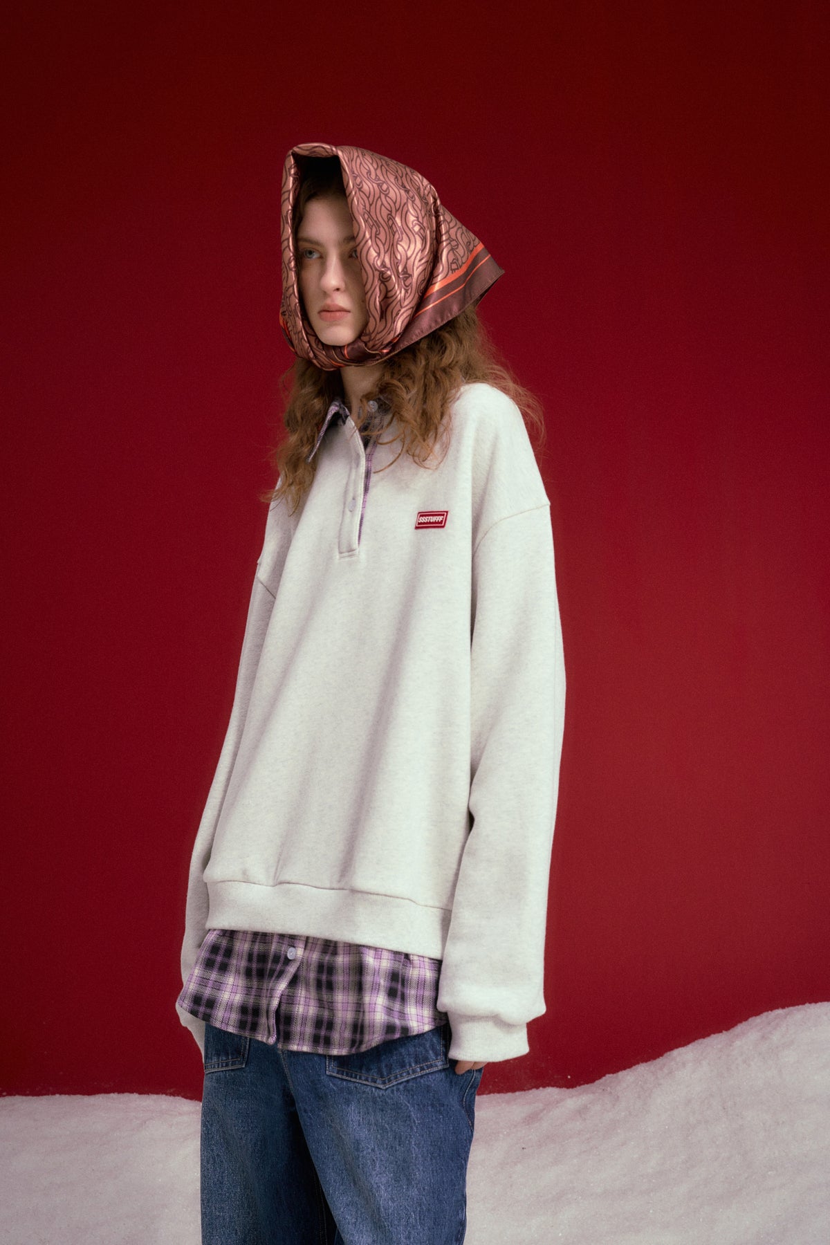 Layered Shirt Crewneck in oatmeal marl, spliced with a checked shirt collar and hem. Worn on a model, waist-up view.