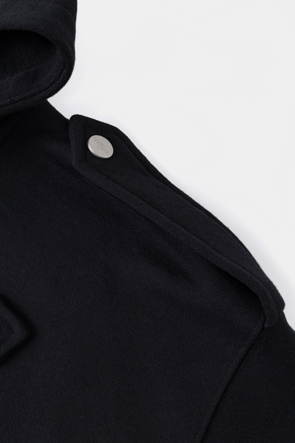 Detail of the shoulder epaulette and its contrast snap fastener.