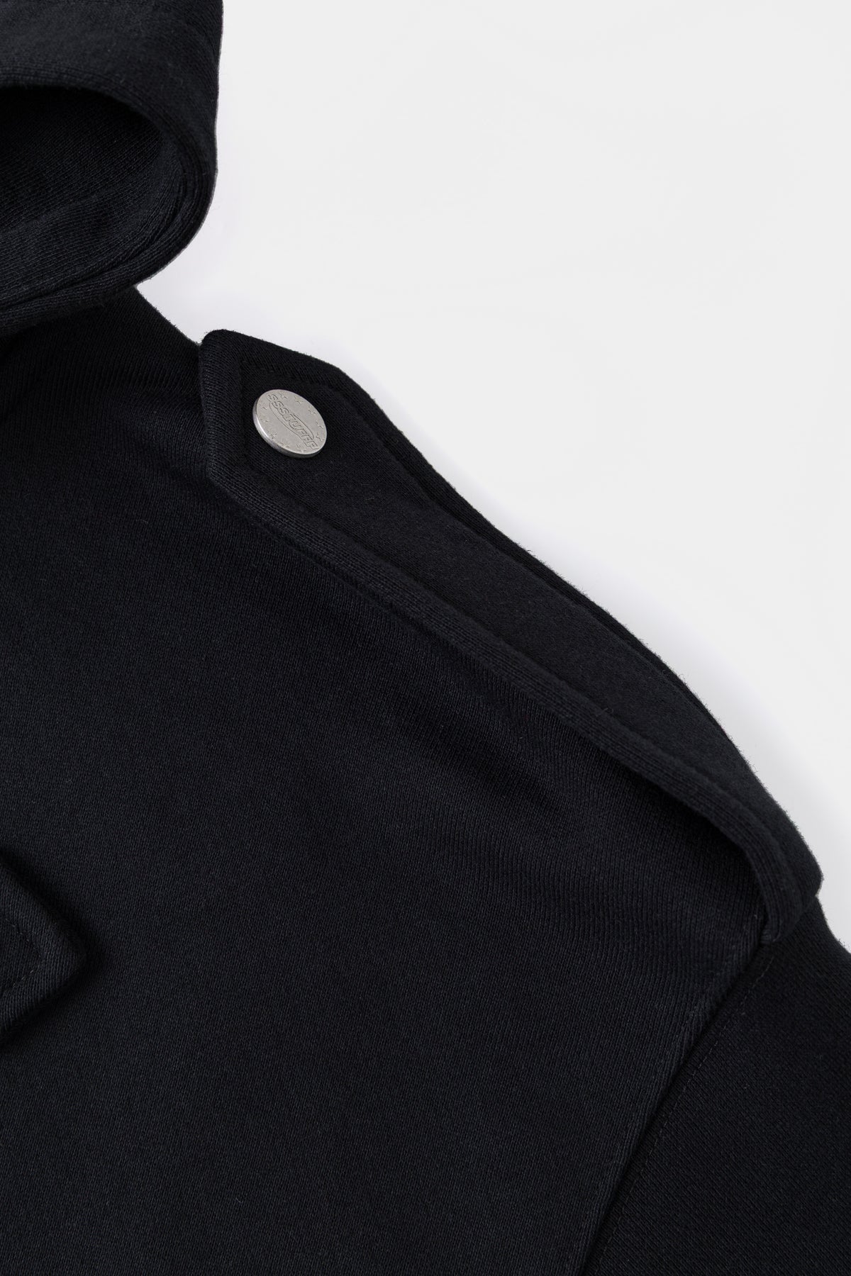 Detail of the shoulder epaulette and its contrast snap fastener.