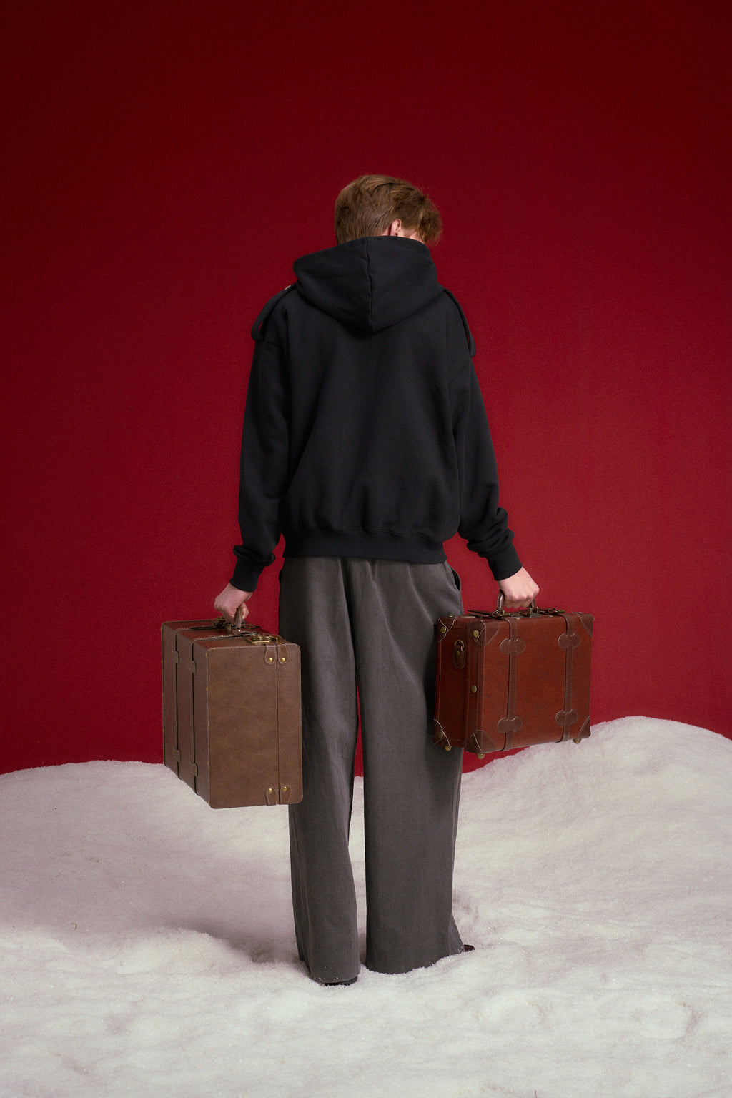 Lobby Boy Hoodie in black, with concierge chest closures and shoulder epaulettes. Worn on a model, full-length back view.