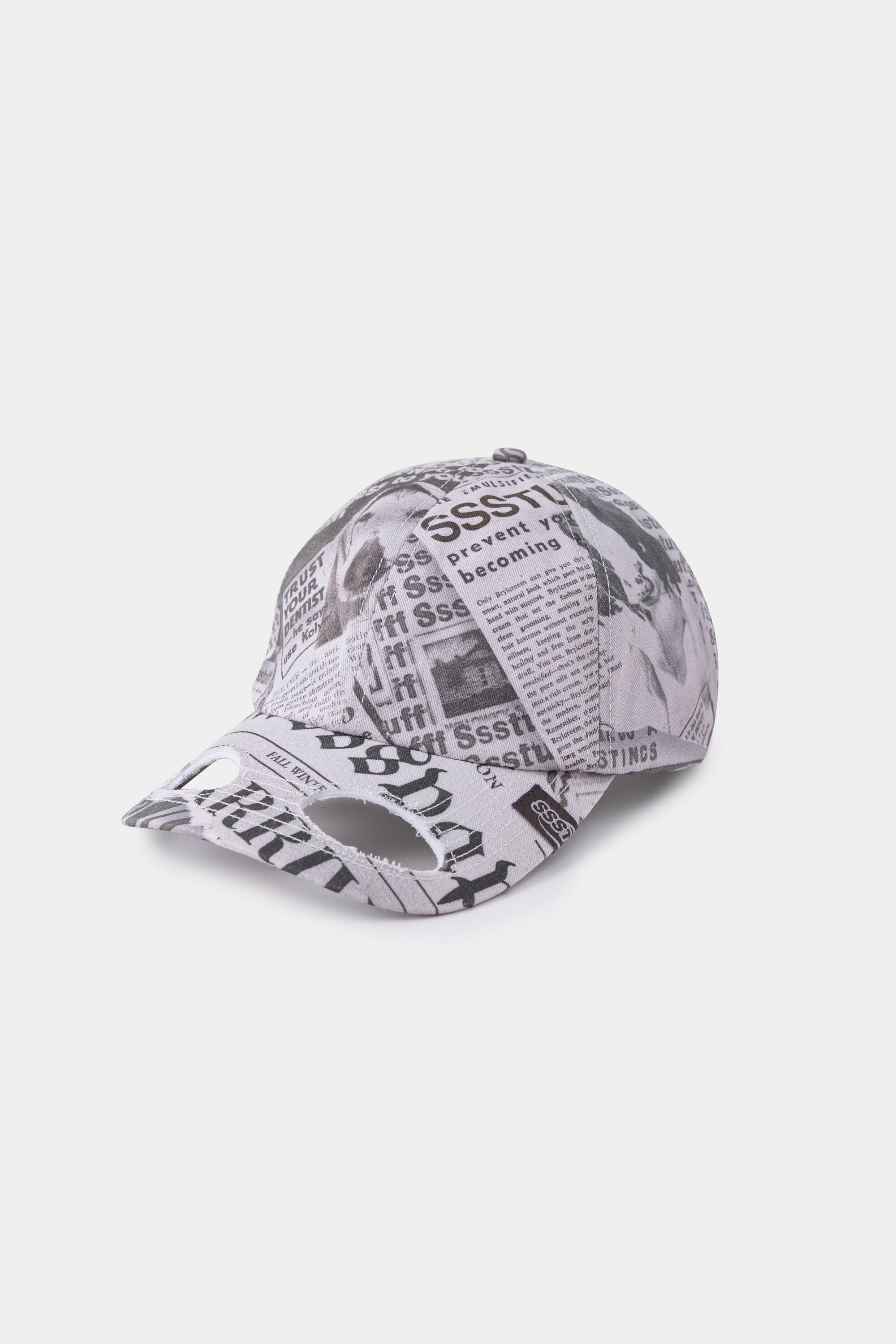 Newspaper Spy Cap in all-over newsprint print, a six-panel cap with a curved brim.