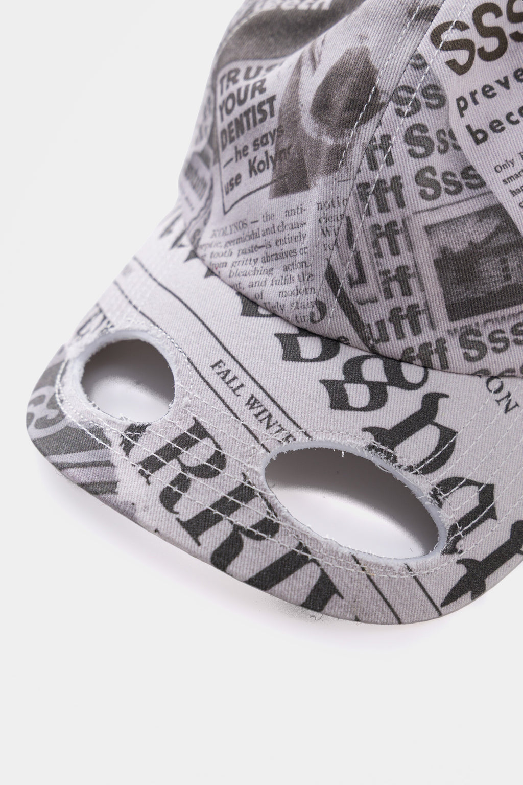 Close-up of the brim, with two eye openings cut through the printed headlines.