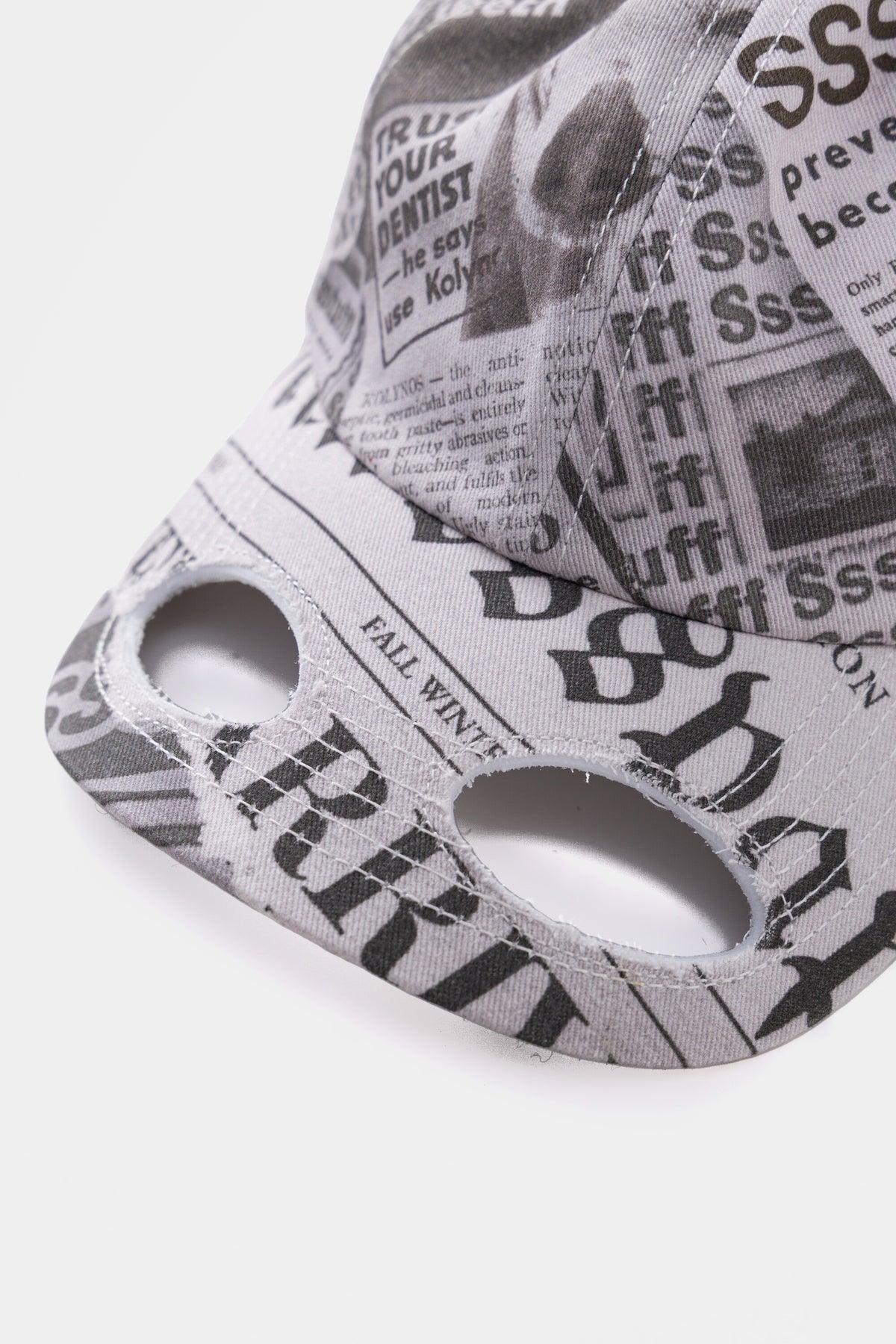 Close-up of the brim, with two eye openings cut through the printed headlines.